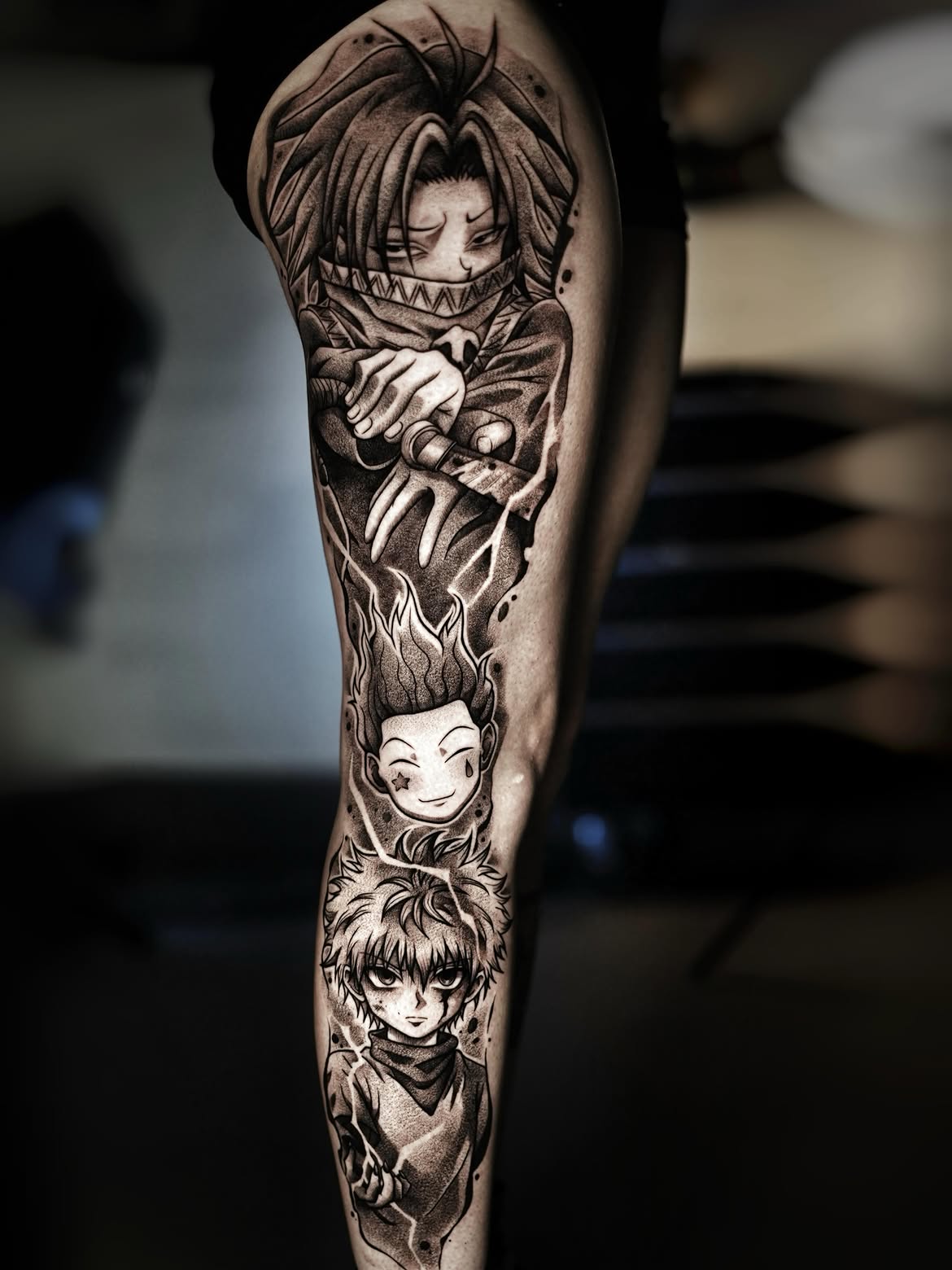 Pierna completa tatuada con personajes de Hunter x Hunter en negro y gris